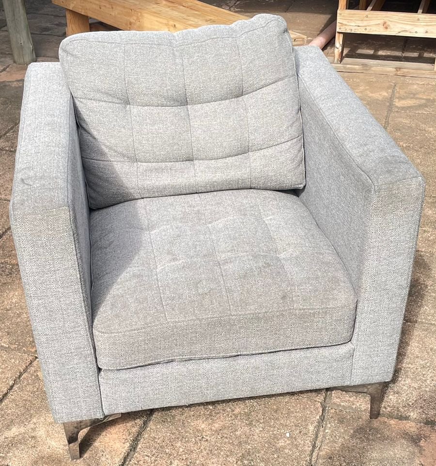 Grey armchair before cleaning, showing body oil and soiling across the seat cushion