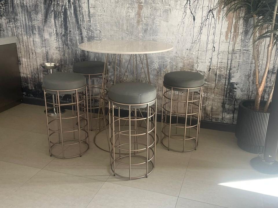 Four grey upholstered bar stools around a counter-height table after cleaning