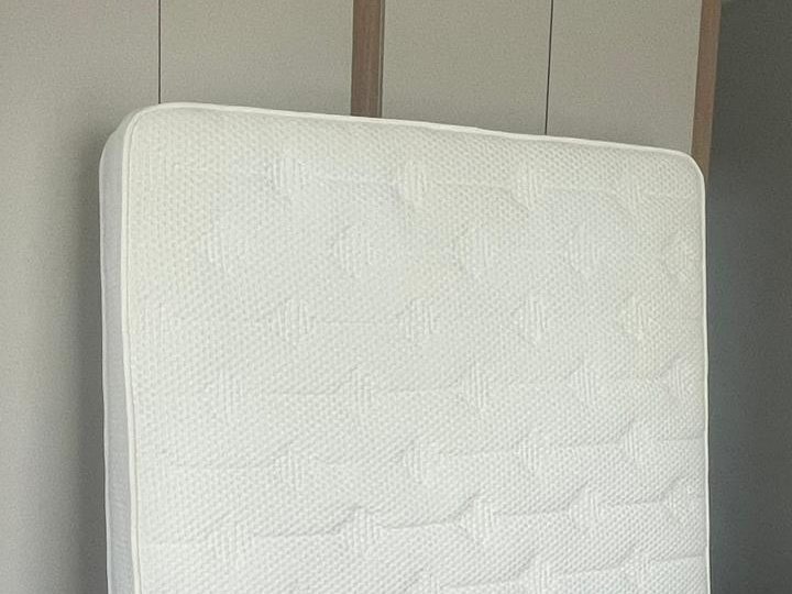Queen mattress standing against a wardrobe after deep cleaning, drying in a bedroom