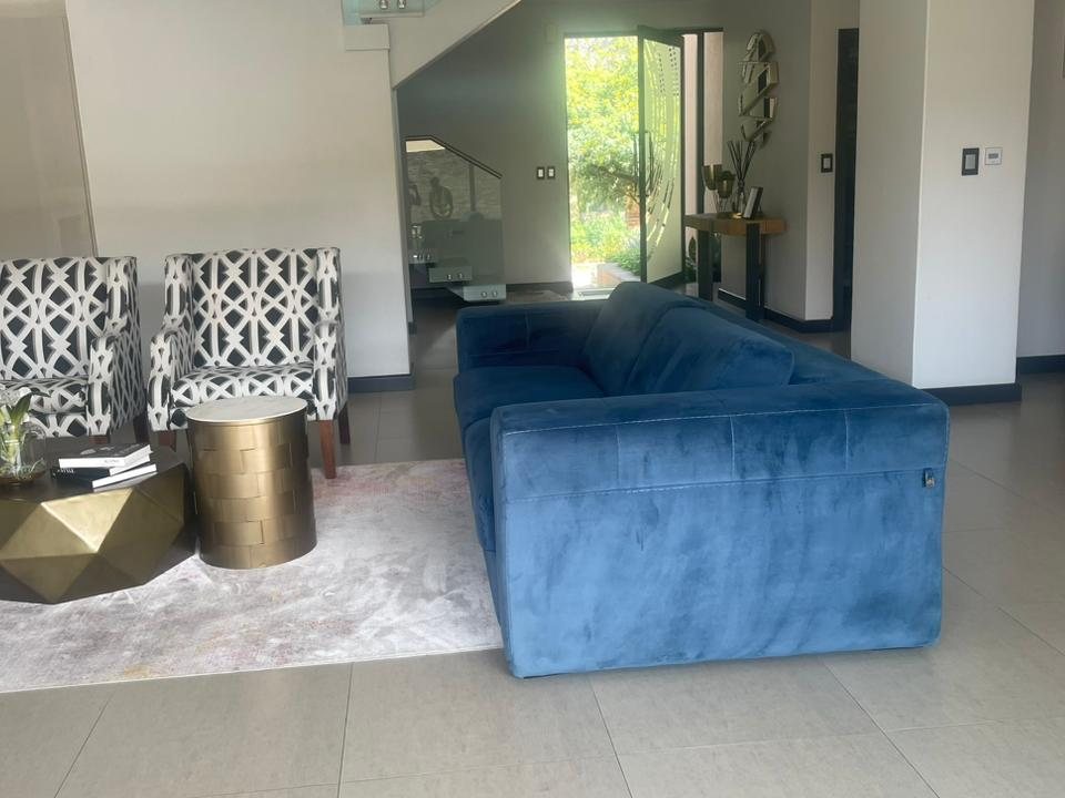 Blue velvet three-seater sofa in a lounge after cleaning and fabric protection